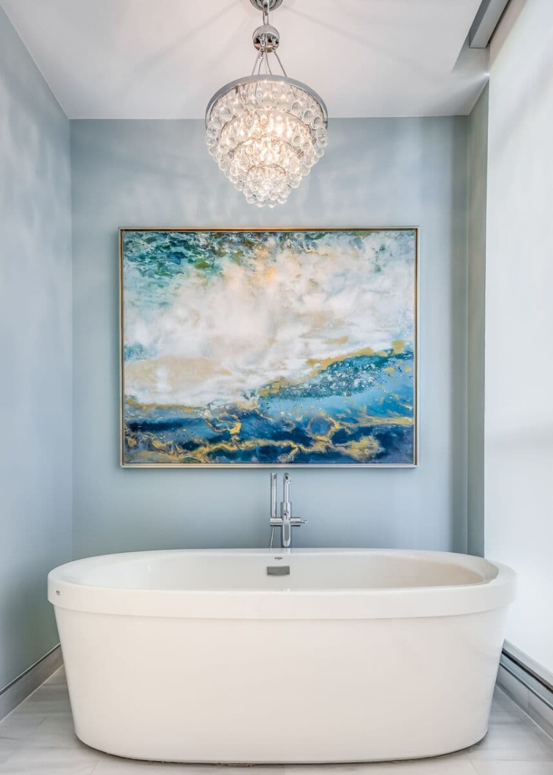Modern Lighting Ideas from One X One Design. This bathroom with blue walls featured an oval bathtub in white, a painting in blue and gold colors and suspension light.